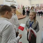 Harcerka rozdaje flagi Polski