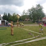 Uczniowie rozwijają wąż strażacki - na konkursie.