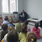 Uczniowie słuchają książki czytanej przez pana Wójta.