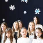Grupa dziewcząt śpiewa na szkolnej Wigilii.