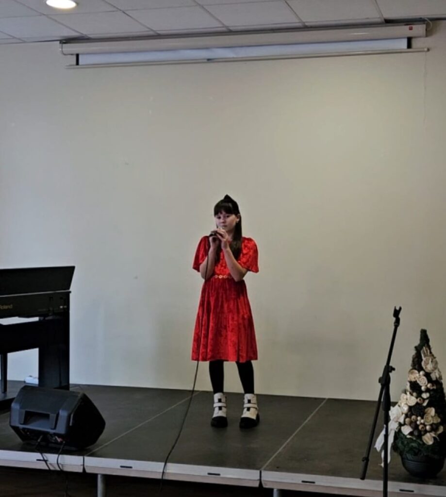 Uczennica śpiewa na scenie w czasie konkursu wokalnego.